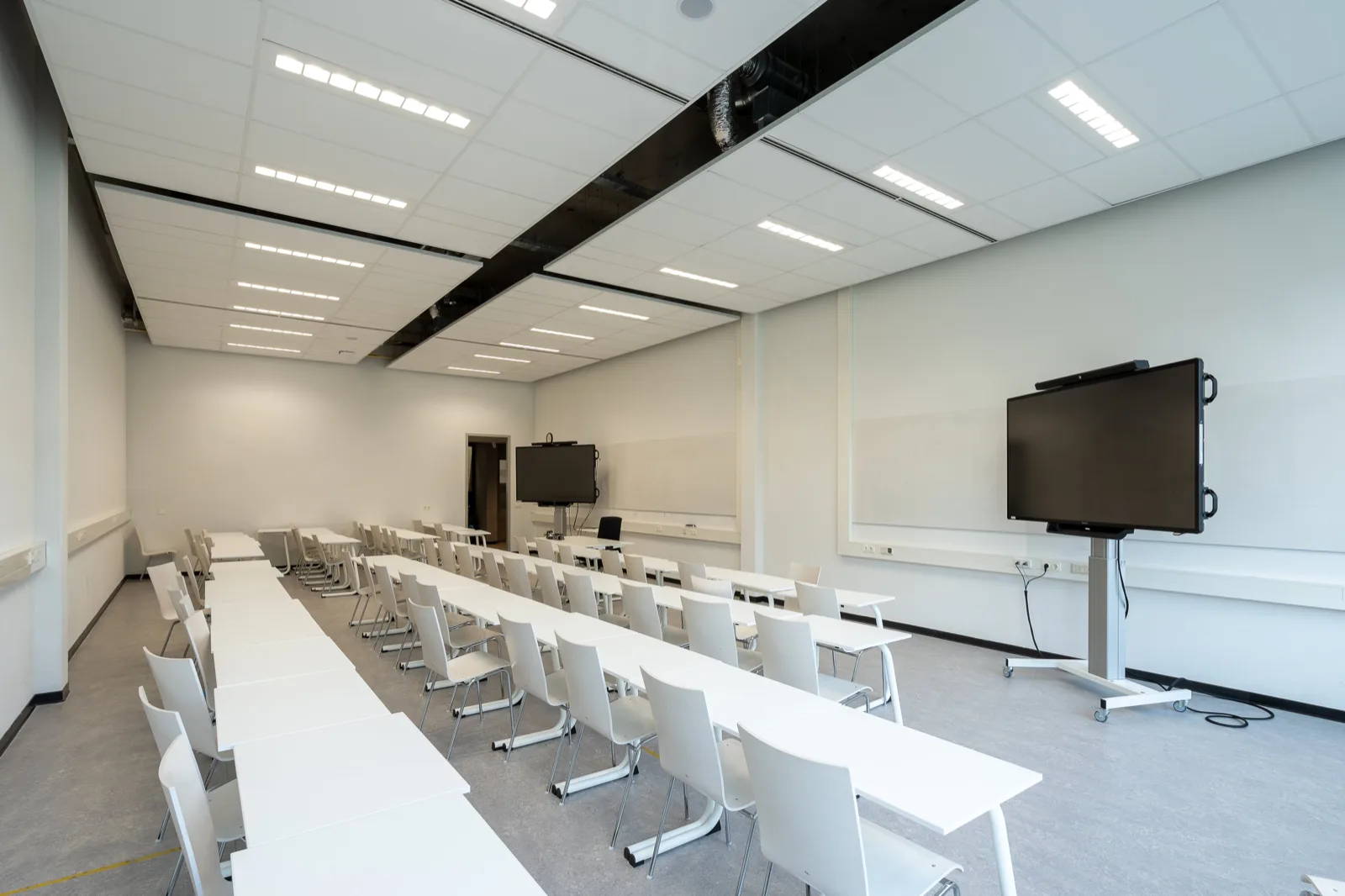 Lecture room with screens and presentation equipment ready for a class.
